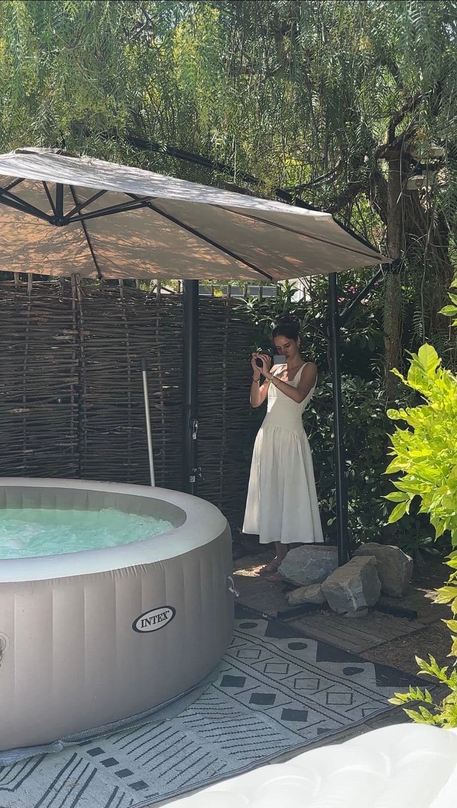 Silia Zeraoui en plein tournage dans un jardin, smartphone en main